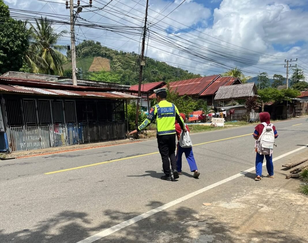 Kurangi Risiko Kecelakaan Pelajar, Ditlantas Polda Sulbar Gencarkan Pengaturan Arus Lalu Lintas Personel Ditlantas Polda Sulbar saat membantu pelajar menyeberang jalan